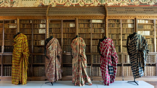 Five mannequins line up against a bookcase at Blickling, wearing colourful African textiles